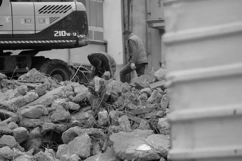 Worker sweeping heavy debris during rough construction phase