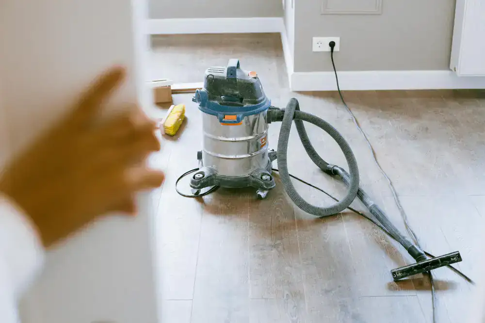 Professional cleaner using a HEPA vacuum on a newly constructed wall