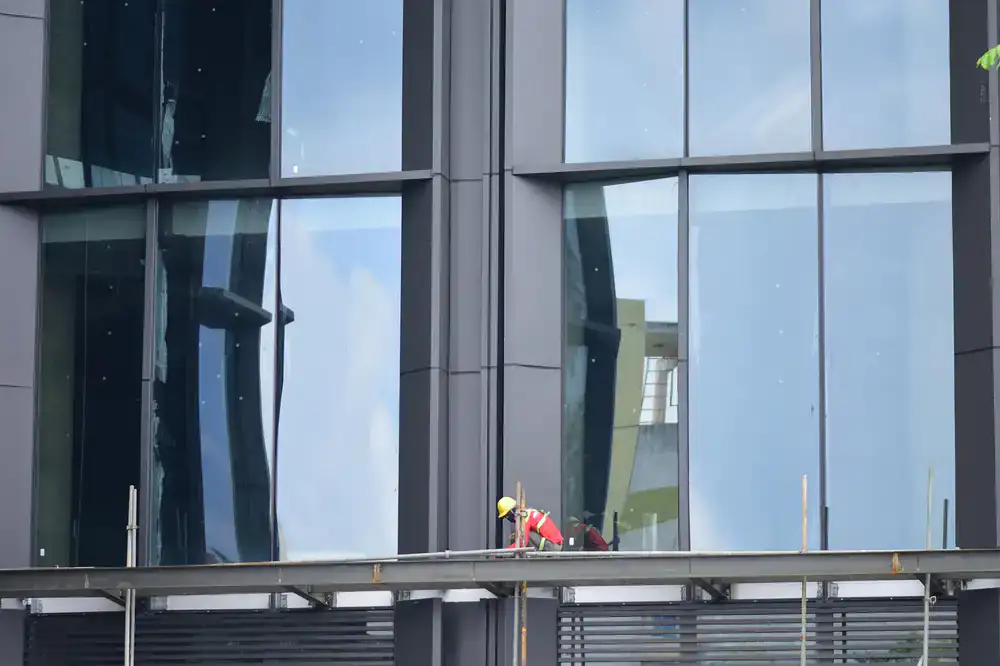 Technician meticulously cleaning window tracks and frames to remove construction dust